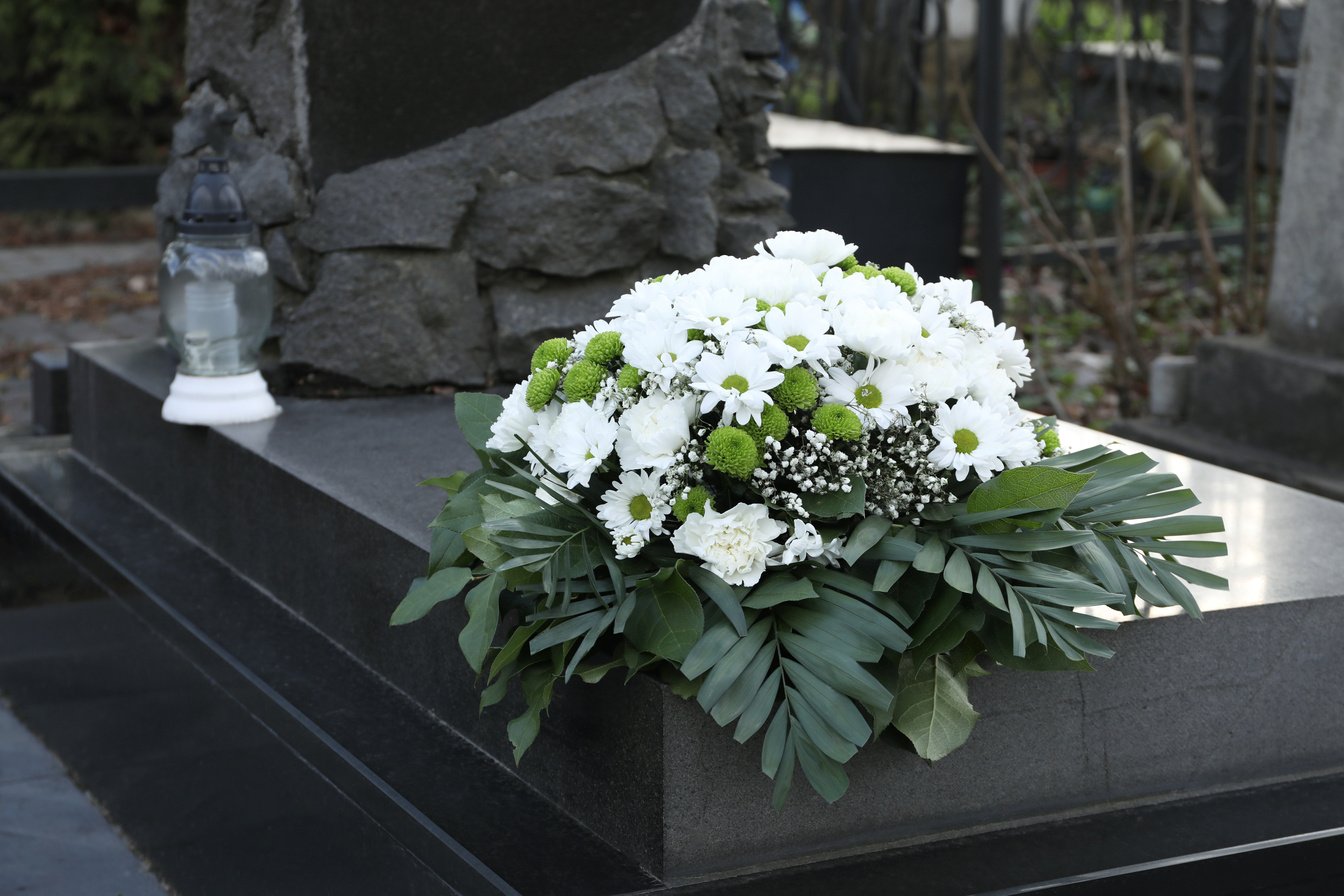 Funeral Wreath of Flowers on Granite Tombstone in Cemetery